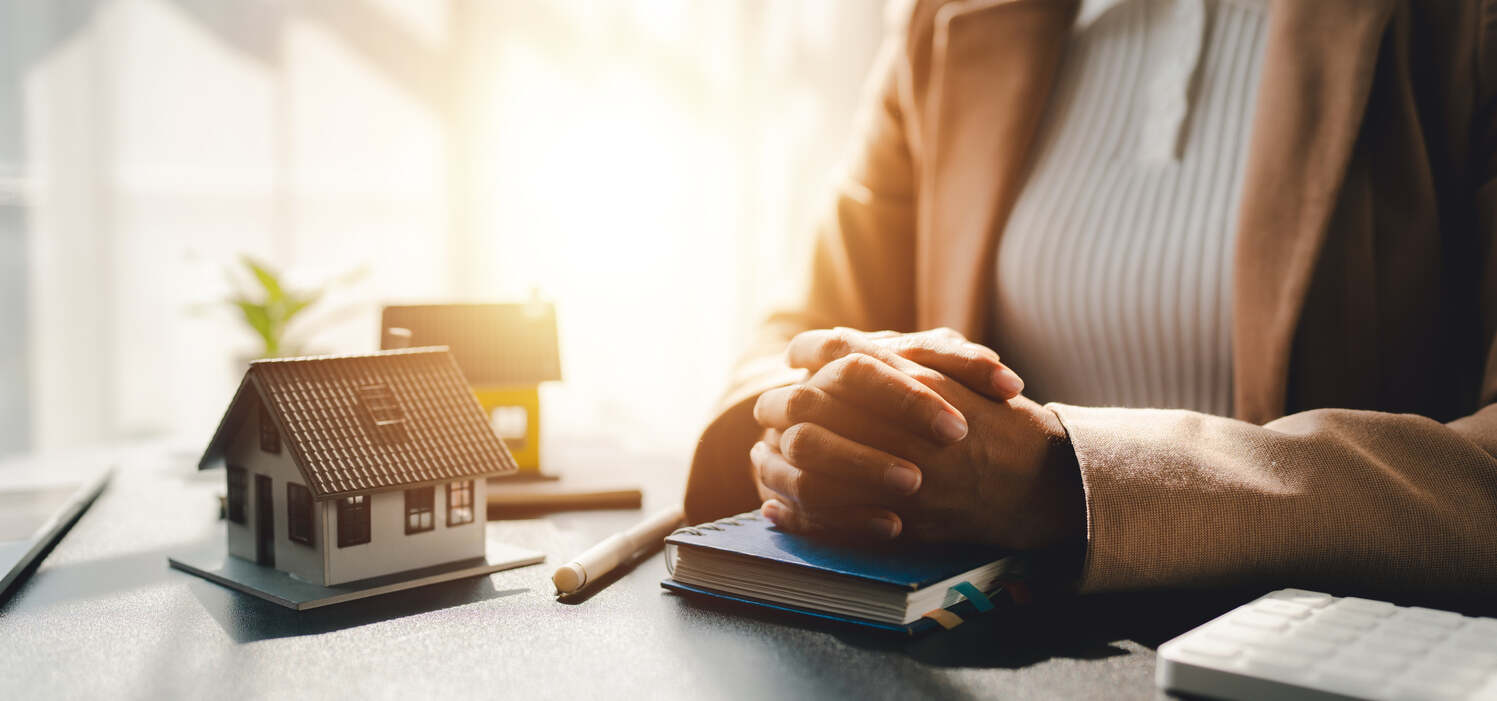 Clasped hands and a miniature house, symbolizing property management and compensation
